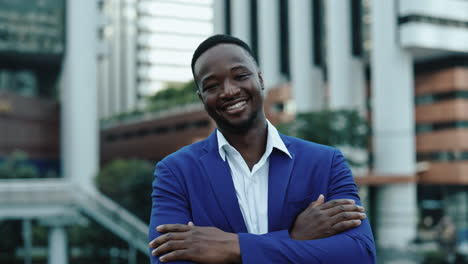 confident african american businessman posing in city with arms crossed
