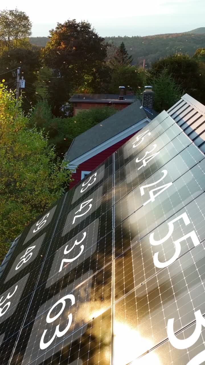 Ripresa aerea verticale del tetto di una casa americana con pannelli solari e animazione dei livelli di energia della batteria al tramonto.