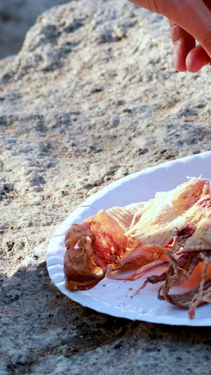 손은 야외에서 달한 소스와 함께 오징어를 준비하고 있습니다.