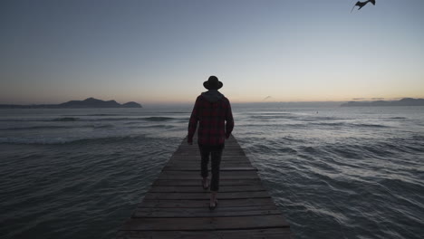 guy walks down a bridgte to the sea of mallorca