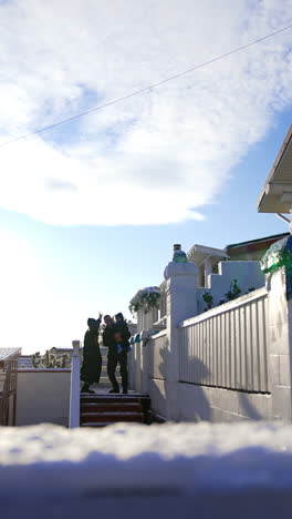 Happy dancing family of three standing on the stairs. Mom, dad and son outdoors in winter. Vertical video.