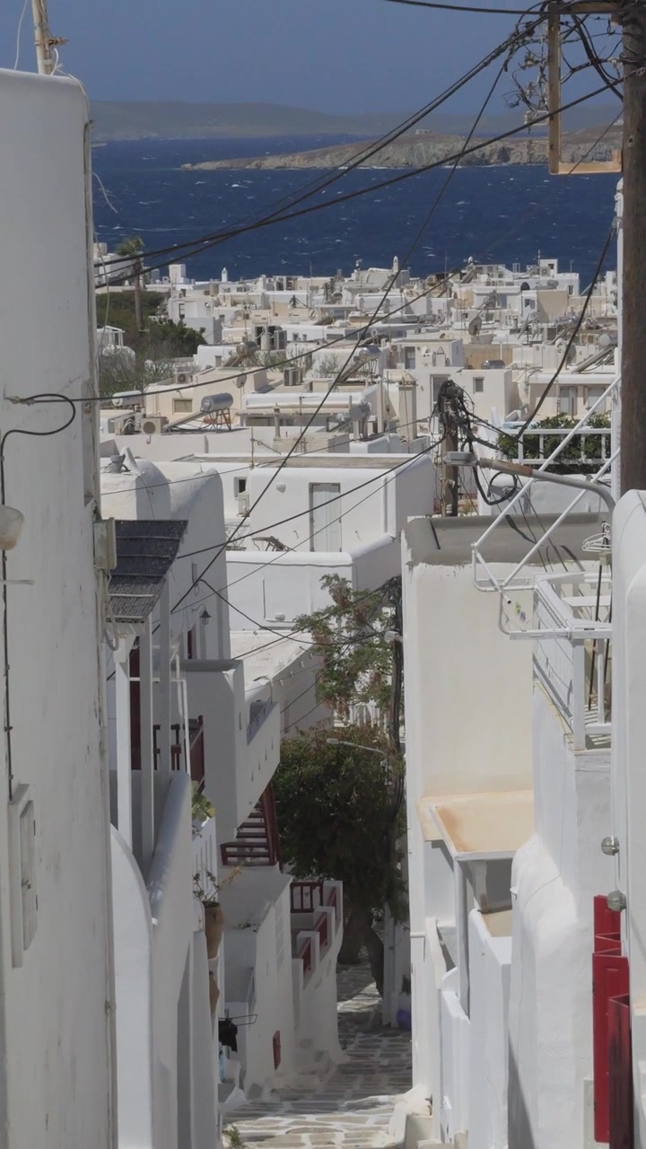 Vista verticale di uno stretto vicolo imbiancato a calce con un sentiero lastricato che si snoda tra le tradizionali case cicladiche a Mykonos, Grecia