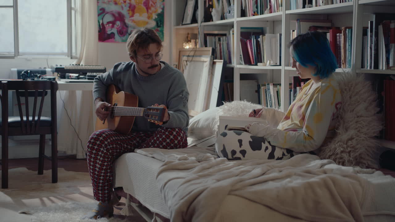 Musician Playing the Guitar and Talking with Girlfriend about Book
