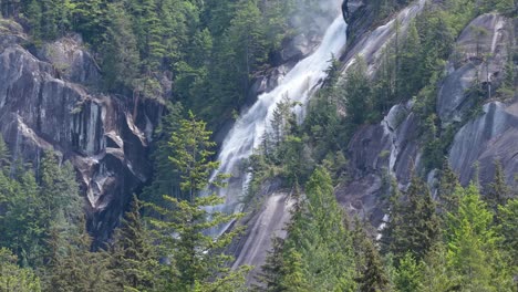 powerful waterfall flowing down a majestic granite mountain amidst lush green forest in british columbia canada