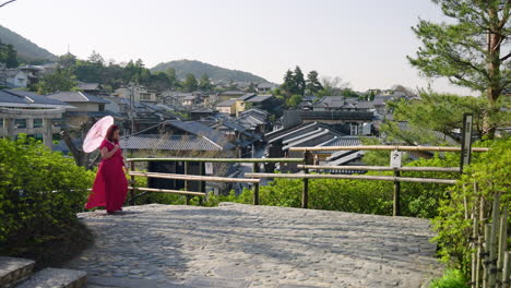 female traveler with paper umbrella exploring view from yasaka pagoda viewpoint in kyoto, japan. dolly-in shot
