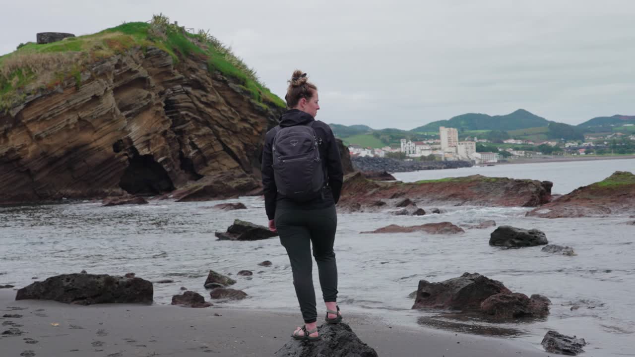 mujer cerca del borde del agua cerca de una costa rocosa en ponta delgada, azores, portugal