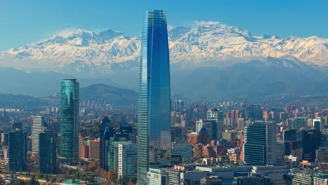 tilting shot of the costanera tower dominating the skyline with the andes behind