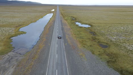 un gris 2021 mazda 3 avanza a lo largo de una carretera islandesa, el viaje destacado por llanuras verdes abiertas y un cielo nublado, encapsulado en suave 4k