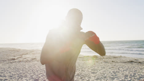 Hombre-Afroamericano-Enfocado-En-Boxeo,-Haciendo-Ejercicio-Al-Aire-Libre-Junto-Al-Mar