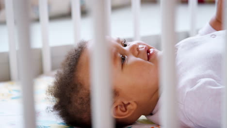 niña acostada de espaldas en la cuna de la guardería y sonriendo