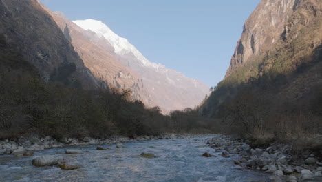 nepal drone shot of bright langtang himalaya with snowy peaks below a peaceful river shining in sunset landscape of trees and adventurous trekking trails highlighting famous tourism trekking region