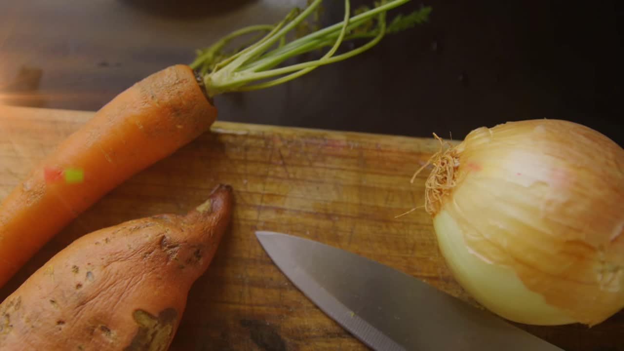 Shifting sunlight sweeping flares across root veggies and knife on board creating organic appeal