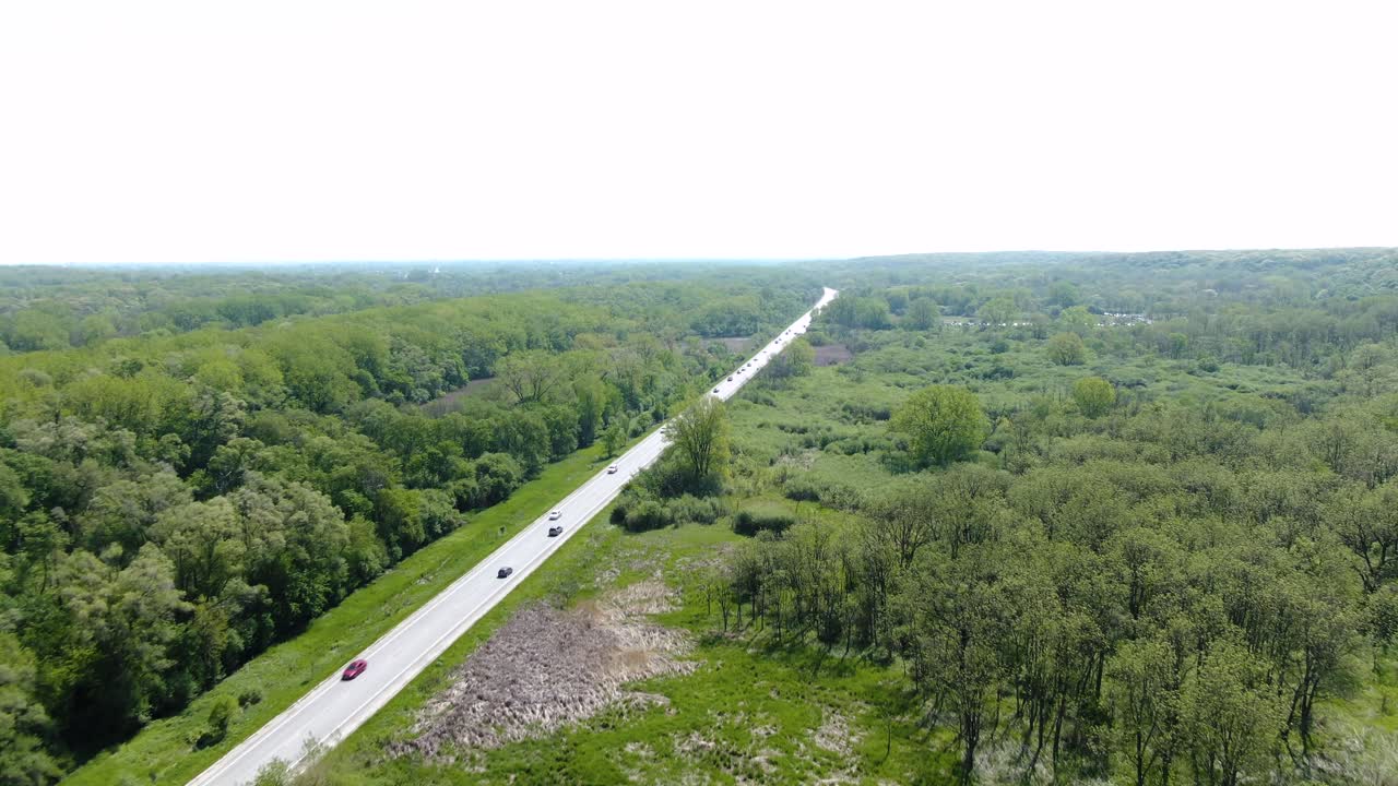toma aérea de un camino rural que atraviesa un espeso bosque en las llanuras