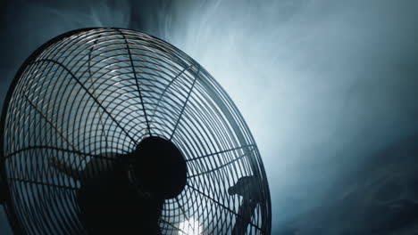 fan blades rotate in rays of light and fog. close-up shot