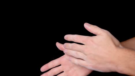 A-person-rubbing-and-dusting-his-hands-with-chalk-powder,-isolated-on-black-background