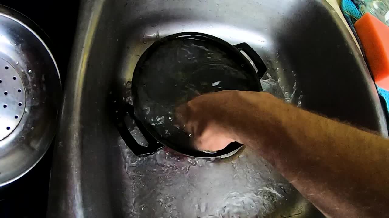 SLOWMOTION - Rengøring af en lille gryde med en hånd i en køkkenvask
