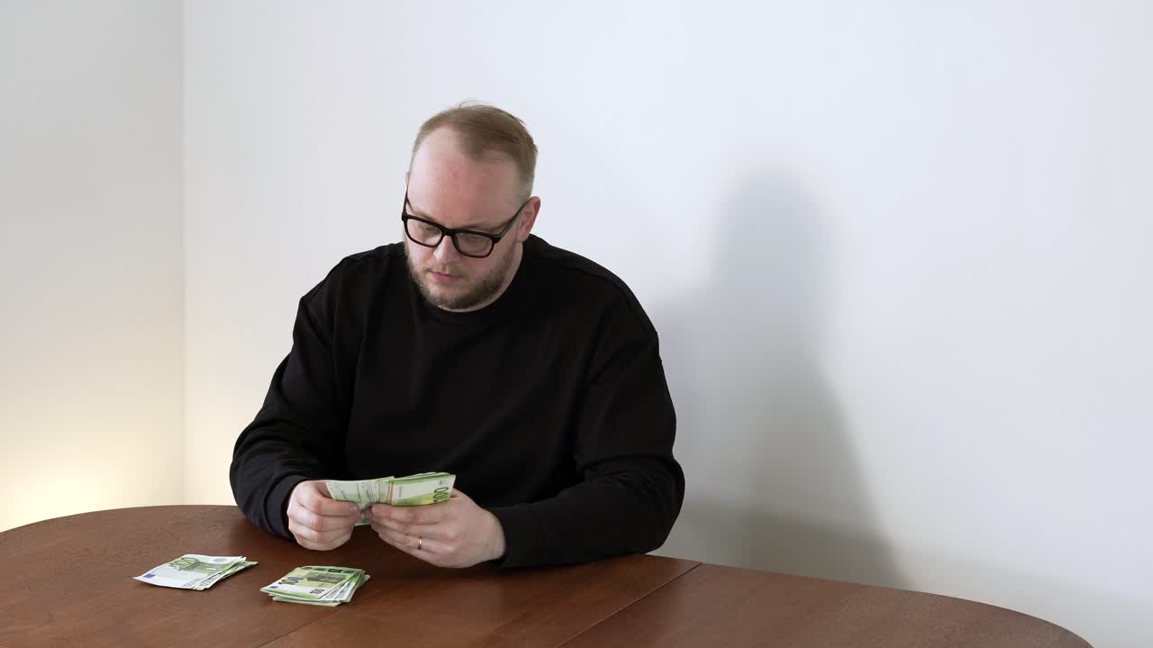 Vuxen man räknar lugnt kontanter på bordet, organiserar personlig budget. Koncept för utgiftskontroll, ekonomisk förvaltning och vardaglig penninghantering.