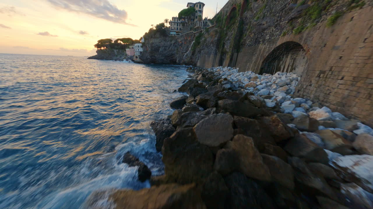Drone FPV che corre lungo la costa italiana, mostrando scogliere, case sul mare, archi nella roccia, poi tornando indietro per rivelare la costa