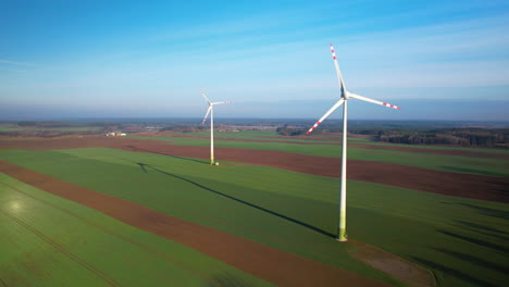 windmills or wind turbines generating electric power, epic aerial view sustainable, renewable wind energy farm plant on cinematic green fields beautiful spring environment background with copy space