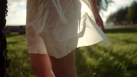 Una-Mujer-Joven-Con-Un-Vestido-Blanco-Transparente-Parada-Contra-La-Luz-Del-Sol-En-Un-Campo-Por-La-Noche