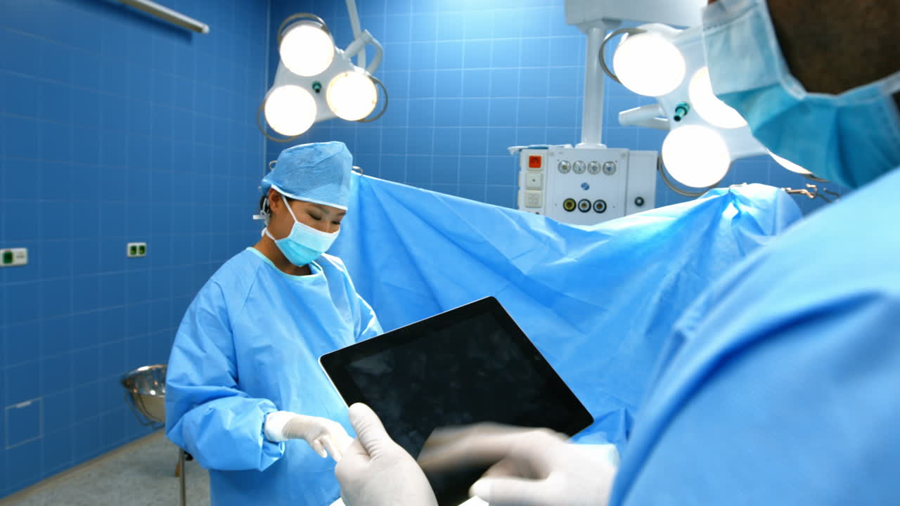 Premium stock video - Surgeon using digital tablet while coworker ...