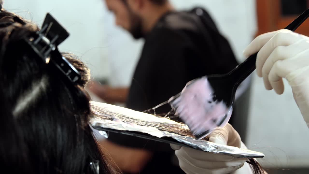 Parrucchiera che tinge i capelli della sua cliente