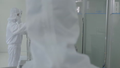 pharmaceutical factory manufacturing worker in protective clothing gear operating production line in sterile environment