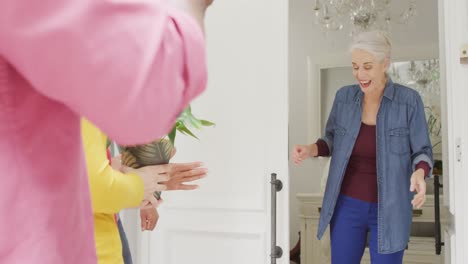 animation of happy caucasian senior woman welcoming friends in doorway