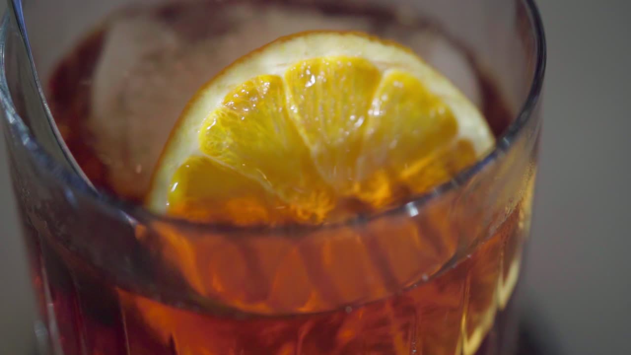 revolviendo suavemente un cóctel con hielo y una rodaja de naranja
