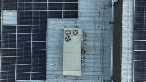modern solar panels and rotating ventilators on roof of building in america. aerial rising top down shot. production of cool air and green energy in usa