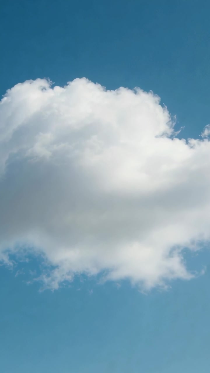 Video vertikal: Awan kumulus besar melayang bergerak ke kanan oleh angin di langit biru, gumpalan-gumpalan terbentuk