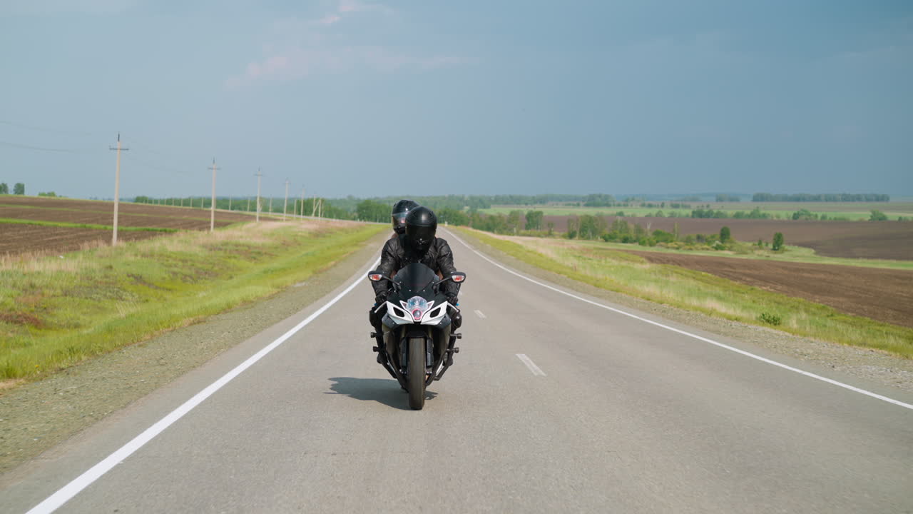pareja disfruta montando una motocicleta a lo largo de la carretera entre los campos