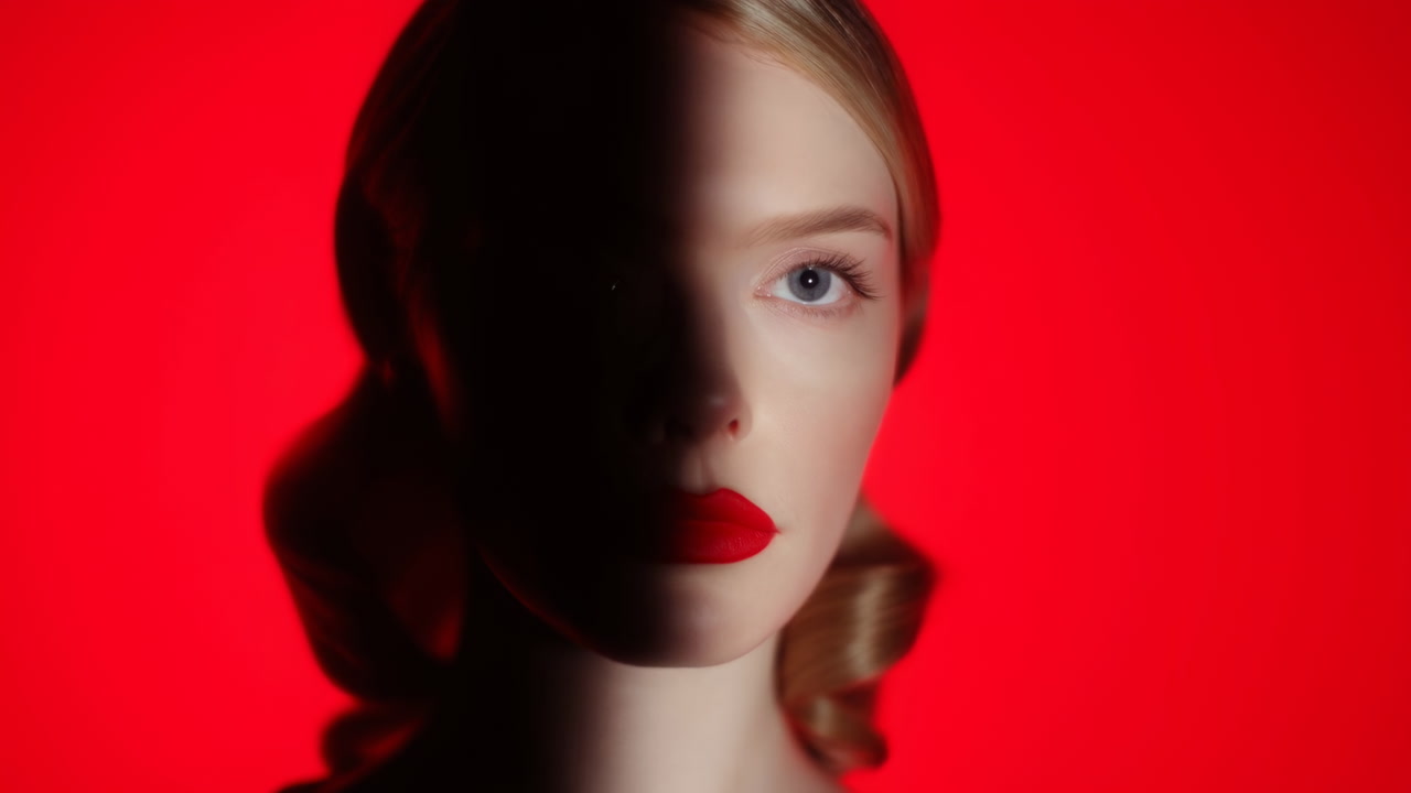 Splitlit Portrait Against Red Backdrop. Dramatic Studio Headshot With Half Face In Shadow And Bold Red Lips,