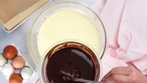 baking chocolate brownies and using a white electric mixer to mix the batter. making brownies on a white background surrounded by eggs, pink napkin and a baking pan. in the kitchen making a dessert