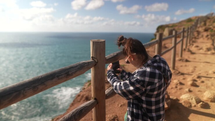 Donna che scatta foto a un punto panoramico costiero