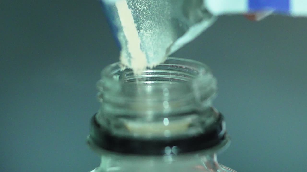 Close Up Shot of Powdered Packet Drink Being Poured into Bottle
