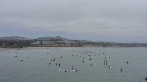 A-beautiful-aerial-drone-shot,-flying-over-surfers-towards-the-beach,-Dana-Point---Orange-County---California