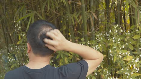 남자는 가려운 두피 때문에 산만해지기 때문에 아름다운 대나무 꽃밭을 즐길 수 없습니다.
