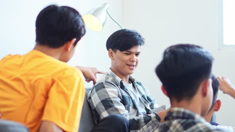 group of male gamers experiencing defeat together on couch while playing mobile gaming on smartphone