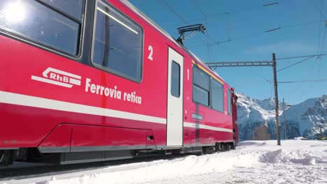 red panorama train passing on a sunny day in the mountains in alp grum, switzerland