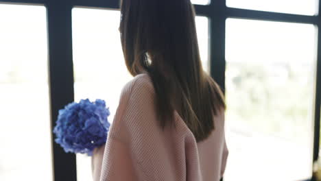 woman with hydrangea by window