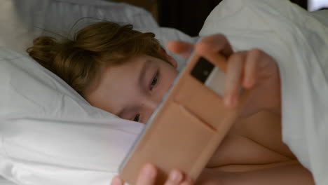 teenager in bed with gadget