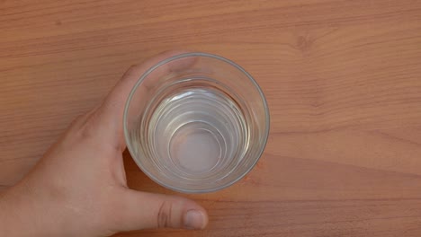 분홍색 알약을 먹고 테이블에 물 한 잔을 다시 놓는 여자