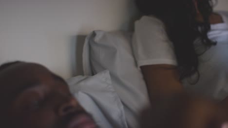 close up of couple at home at night both looking at their mobile phones in bed 2