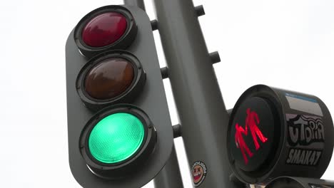 city traffic light adorned with stickers is seen changing from green to red for vehicles and vice versa for pedestrians