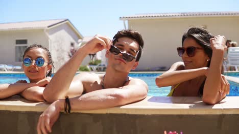 feliz grupo de amigos disfrutando de la fiesta de la piscina de verano salpicando sus piernas en el agua