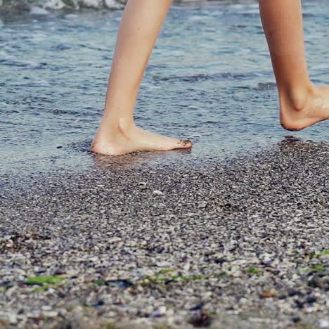 female legs close up. woman walking on beach barefoot at sunset. slow motion.