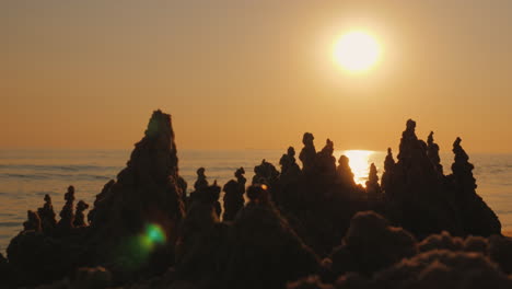 Silhouette-Of-A-Sand-Castle-Against-The-Background-Of-The-Setting-Sun-And-Sea-Waves-4K-Video