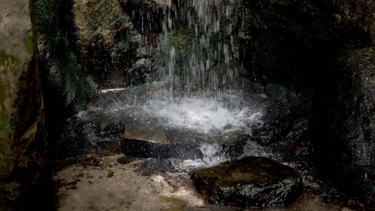 petite chute d'eau frappant le sol rocheux plat, éclaboussant sur le bord
