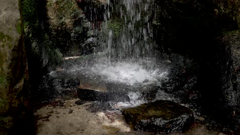 Pequeña-Cascada-Que-Golpea-El-Suelo-Rocoso-Plano,-Salpicando-El-Borde